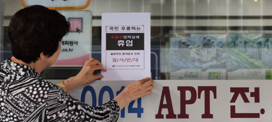 서울 시내의 한 부동산중개업소에서 관계자가 중개수수료 인하 정책에 반대하는 휴업 안내문을 붙이고 있다. <연합뉴스>